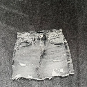 Grå jeanskjol med slitningar från Zara - Snygg grå jeanskjol från Zara i kort modell med slitna detaljer och fransig nederkant. Det är mycket bra skick på kjolen då den nästan aldrig blivit använd💕💕