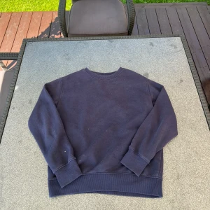 Mörkblå sweatshirt i bomull - En basic mörkblå sweatshirt med rund hals och långa ärmar. Tröjan har breda muddar vid ärmslut och nederkant, vilket ger en skön och avslappnad passform. Perfekt för chill dagar eller när du vill ha en enkel stil.