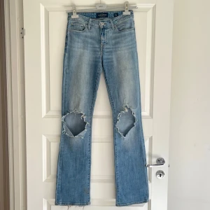 Lucky Brand ljusblå bootcut jeans - Jättesnygga ljusblå jeans från Lucky Brand med bootcut passform och stora slitningar vid knäna i modellen ”Lolita Boot”. Lite slitna längst ner men passar viben på jeansen. Har varit ett par favoritjeans men som inte passar längre! Storleken är 2/26 long, 36.5 cm tvärsöver midjan och 85 cm i innerbenslängd. 