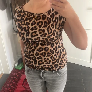 Leopardmönstrad topp med kort ärm - Säljer en snygg leopardmönstrad topp i beige och bruna toner. Toppen har korta ärmar och en rundad halsringning. Den är figurnära och passar perfekt till jeans eller kjol för en cool look.