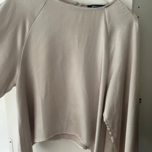 Beige långärmad topp från Gina Tricot - Säljer en stilren beige långärmad topp från Gina Tricot. Toppen har en enkel och clean design med rund halsringning och mjukt, tunt material som känns skönt mot huden. Perfekt för lager-på-lager eller som den är.