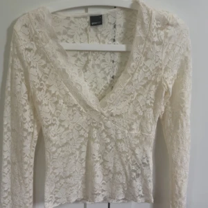 Vit spetsblus från Gina Tricot - Säljer en superfin vit blus från Gina Tricot i storlek S. Blusen är helt i spets med blommigt mönster, v-ringning och långa ärmar. Perfekt att styla med jeans eller kjol. Helt oanvänd då jag fick den i fel storlek. 🤍 nypris 300kr