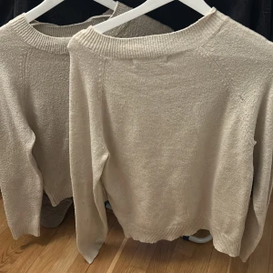 Beige stickad tröja med rund hals - Enkel och stilren beige stickad tröja med rund halsringning och ribbade muddar. Perfekt för lager-på-lager och passar till allt. Mjuk och skön känsla, långärmad och i klassisk modell.