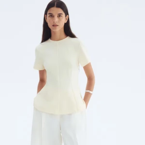 Krämvit figursydd blus med kort ärm - Säljer en krämvit blus med korta ärmar och rund hals. Toppen har en figursydd passform med markerade sömmar som ger en snygg siluett. Materialet är mjukt och lätt, perfekt för en clean och stilren look. Säljer en i XS och en i S! Båda är helt nya med prislappen kvar. 