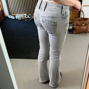 Ljusgrå bootcut Pepe Jeans - Säljer ett par ljusgrå bootcut jeans med låg midja och dubbla knappar i midjan. Dessa sitter AMAZING men har dessvärre blivit lite för korta för mig🥹. Storlek W24 L32, hitta fler snygga jeans i min profil!!⭐️ Värt att nämna är också att de är väldigt diskret och snyggt sydda vid skrevet och vid ena fickan, men det är knappt märkbart och jag har använt de så utan problem, skickar självklart bild på detta efter förfrågan. 