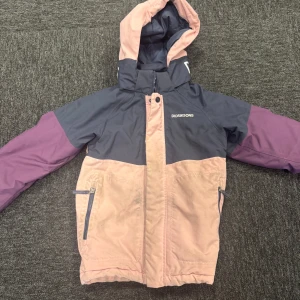 Färgglad jacka från Didriksons - Jacka från Didriksons i snygga färgblock med mörkblå, ljusrosa och lila partier. Utrustad med huva, dragkedja och två fickor framtill. Perfekt för dig som gillar en sportig och färgstark stil.