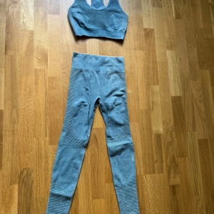 Blå grön, träningstights med matchande topp - Snygga blå gröna tights med hög midja och ventilerande meshdetaljer längs benen med matchande topp till.  Perfekta för gymmet eller yoga, sitter tight och följer kroppen. Materialet är stretchigt och mjukt för maximal rörelsefrihet.