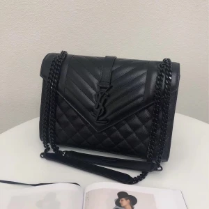 Svart quiltad axelväska från Saint Laurent - Säljer en svart quiltad axelväska från Saint Laurent med ikoniskt YSL-emblem framtill. Väskan är i skinn med kedjerem i svart metall och har ett stilrent, lyxigt uttryck. Perfekt storlek för det viktigaste och med magnetlås för enkel öppning.