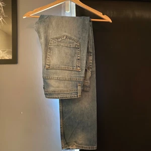 Ljusblå slimjeans från Dressmann - Säljer ett par klassiska ljusblå jeans från Dressmann med snyggt slitna detaljer och femficksmodell. Jeansen har normal passform och raka ben, perfekt för en avslappnad stil.  Har modell slim fit och är i grymt skick