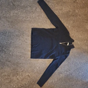 Mörkgrå halvzip-tröja från Sandro - Mörkblå stickad tröja från Sandro med hög krage och snygg half zip-dragkedja framtill. Tröjan är långärmad och har en clean, stilren look som passar perfekt till jeans eller dressade byxor. Materialet är mjukt och känns lyxigt mot huden. Det är 100% ull och storleken XS eller ca 36.