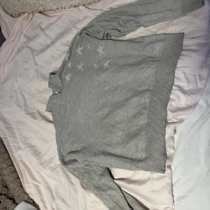 En jätte fin stickad tröja med stjärnor från Gina!! - stickad tröja med ribbade muddar och diskreta stjärnor på ena axeln. Använd ett antal gånger men i väldigt bra skick. Storlek 158-164.köparen betalar frakt.