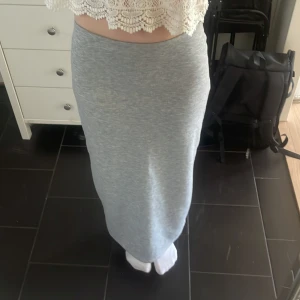 Ljusgrå långkjol - Säljer en ljusgrå långkjol. Kjolen har en enkel och clean look med en diskret slits baktill. Perfekt till sommaren.