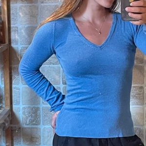 v-ringad tröja - Säljer en blå v-ringad tröja från Cubus i storlek M. Tröjan har lång ärm, ribbad nederkant och är i en slim passform som sitter snyggt på kroppen. Perfekt för dig som gillar enkel och stilren look.