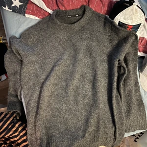 Grå stickad tröja med rund hals - En stilren grå stickad tröja med rund halsringning och lång ärm. Perfekt för lager-på-lager och passar till både jeans och chinos. Tröjan har en klassisk passform och är tillverkad i ett mjukt stickat material som håller dig varm under kyliga dagar. Och två Tshirt 