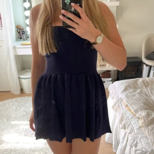 Mörkblå kort klänning från Zara - Supersöt mörkblå klänning från Zara med tight överdel och utställd kjol. Klänningen är ärmlös och har en enkel, stilren design som känns både trendig och klassisk. Perfekt för dig som gillar minimalistiska vibes och vill ha något som sticker ut utan att vara för mycket.
