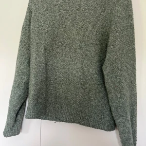 Grön stickad tröja från Vero Moda - Mysig grön stickad tröja från Vero Moda i storlek XS. Tröjan har en klassisk rund halsringning, långa ärmar och ribbade muddar vid ärmslut och nederkant. 