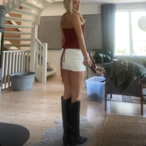 Svarta cowboy boots med klack - Säljer ett par svarta cowboy boots i skinnimitation med markerad klack och klassiska western-detaljer. Bootsens höga skaft och spetsiga tå ger en riktigt snygg siluett. Perfekta att styla med kjol eller jeans för en trendig look.