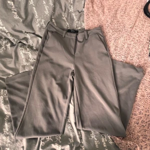 Gråa kostymbyxor - Snygga grå kostymbyxor från Vero Moda med vida ben och hög midja. Byxorna har bälteshällor och klassisk kostymskärning, perfekta att styla med en crop top eller stickad tröja. Materialet känns mjukt och har en stretch.