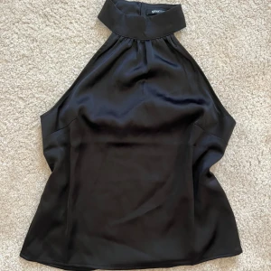 Svart halterneck topp Gina Tricot - Säljer en svart halterneck topp från Gina Tricot i glansigt satintyg. Endast använd en gång! Lite dyrare topp