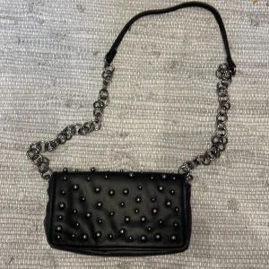 Svart axelväska med nitar från Zara - Cool svart axelväska från Zara i skinnimitation med silvriga nitar på framsidan. 