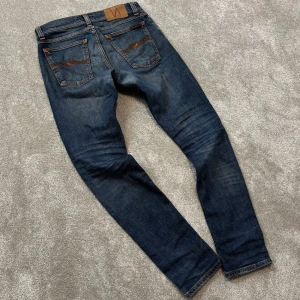 Nudie Jeans - Tja! Säljer dessa schyssta blå Nudie jeans med en snyggt använd stil. Schyssta slitningar på framfickorna. Fint skick, lagade i skrevet men inget som stör. Size 27/30 men sitter som 30/30 ish, midjemått:38,5cm. Ytterbenslängd: 98cm. Skriv vid funderingar!