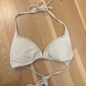 Vit trekantsbikini med knytband - Snygg vit trekantsbikini med knytband i nacken och ryggen. Klassisk modell med vadderade kupor och enkel, stilren design. Perfekt för stranden eller poolen när du vill ha en clean och fräsch look. Säljer en likadan i svart, köper man båda får man de för ett billigare pris!