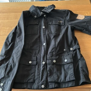 Svart Fjällräven jacka XS - Svart Fjällräven jacka i klassisk modell med flera fickor framtill, tryckknappar och krage. 