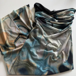 Mönstrad axelbandslös klänning från Zara - Säljer en snygg axelbandslös klänning från Zara med unikt abstrakt mönster i blått, beige och svart. Klänningen har draperad överdel och är figurnära med mjukt, stretchigt material. 