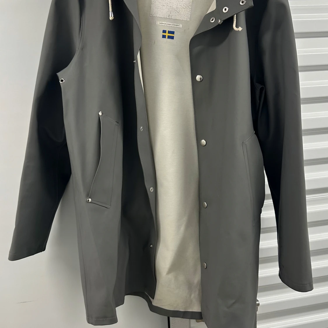 Grå regnjacka med huva och snörning