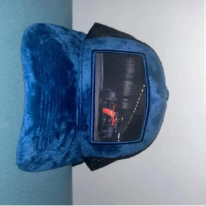 Velvet Keps - Unik F1 i blå sammet med svart baktill. Framsidan har en patch med ett coolt motiv av en Formel 1-bil i tunnel. Kepsen har böjd skärm och justerbar passform. Perfekt för dig som gillar motorsport och vill sticka ut.