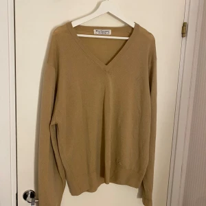 Beige v-ringad tröja från Burberrys - Priset är diskuterbart vid snabb affär!!            Vintage, klassisk beige v-ringad tröja från Burberrys i 100% merinoull, tillverkad i Skottland. Tröjan har lång ärm, diskret broderad logga på ena sidan och en clean, tidlös look.