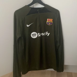 Barcelona tracksuit mörkgrön  - Säljer en långärmad mörkgrön FC Barcelona fotbollströja  med klubbmärke på bröstet och Spotify som sponsortryck. Tröjan har rund hals och är perfekt för dig som älskar Barca.(Endast använd 2 gånger ) pris kan diskuteras MVH.