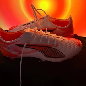 Vita och röda fotbollsskor från Puma - Säljer ett par snygga fotbollsskor från Puma i vitt och orange. Skorna är helt nya (aldrig använts). Du får skolådan och en påse med köpet(bild 5) pris kan diskuteras. spelas på gräs(FG) kan spelas på konstgräs. 