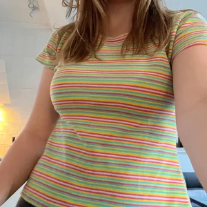 Randig t-shirt från Authentic Style - Säljer en färgglad t-shirt från Authentic Style i storlek M. T-shirten har smala ränder i rosa, gul, grön, blå och orange. Modellen är kortärmad med rund halsringning och normal passform. Mycket fint material! Perfekt för dig som gillar färg!