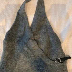 Grå stickad halterneck topp från Zara - Säljer en helt ny grå stickad halterneck topp från Zara med snygg bältesdetalj på sidan i storlek M. Prislappen kvar