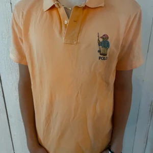 Polo bear pike - Säljer en ORANGE pikétröja från Polo Ralph Lauren med broderad björn på bröstet. Klassisk krage och knappar framtill. På bilden ser den lite gul ut men den är helt orange. Upp för förhandling. Har du någon beundran, hesitera inte att fråga