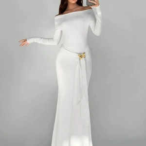 Vit långklänning med offshoulder och knytdetalj - Elegant vit långklänning med offshoulder och lång ärm. Klänningen har en smickrande tight passform och ett dekorativt knytband i midjan med gulddetalj. Perfekt för speciella tillfällen när du vill sticka ut.