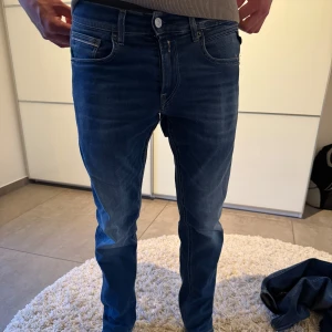 Blå jeansbyxor från Replay - Säljer ett par klassiska blå jeansbyxor från Replay med normal passform och raka ben. Jeansen har fem fickor, dragkedja och knapp i midjan. Perfekta för dig som gillar en tidlös stil.