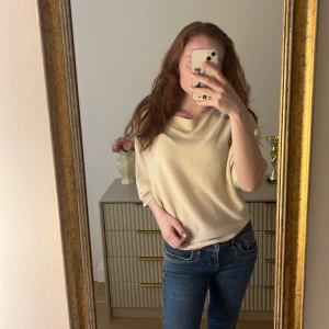 Beige pösig stickad tröja  - Säljer en beige stickad tröja med v-ringning och trekvartsärm. Tröjan är pösig och den är i gott skick.