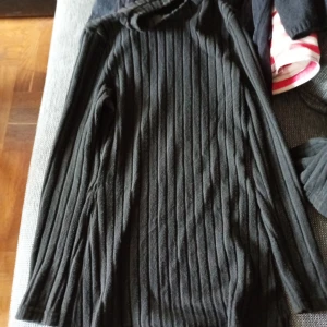 Svart ribbad Tröja med byxor stl L  - Säljer en svart Tröja med byxor med vida ben ,med ribbad struktur. Tröjan har långa ärmar och är figurnära upptill med en rak passform nedtill. Perfekt för dig som gillar en stilren och enkel look.