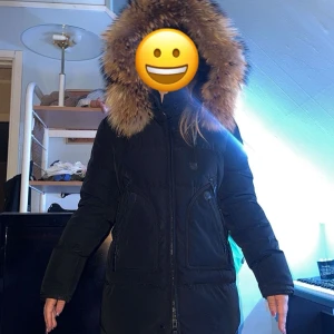 Svart vinterparkas med pälskantad huva från Cecion Sweden  - Säljer en svart vinterparkas från Chamonix med stor pälskantad huva. Jackan har dragkedja framtill, två stora fickor och är långärmad. Materialet är polyester och dun med tvättbjörnspäls på huvan.