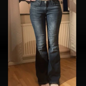 Blå bootcut jeans - Snygga blå bootcut jeans med klassisk femficksdesign och normal passform. Jeansen har en lätt tvättad look och stängs med dragkedja och knapp. Perfekta för dig som gillar en tidlös stil med lite utsvängda ben.