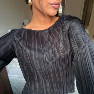 Svart plisserad topp  - Säljer en svart plisserad topp med långa ärmar och öppen rygg med knyt. Toppen har en smickrade  passform och bred, rund halsringning. Perfekt för dig som gillar unika detaljer och stilren design. Öppen i ryggen och går att ha der fram om man vill det också!!😍🍓passar xs-s