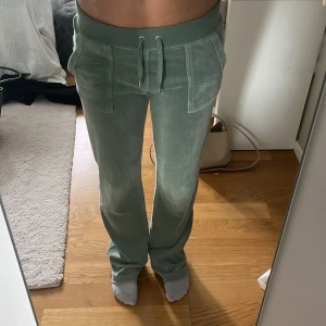 Juicy byxor  - Snygga gröna mjukisbyxor med dragsko i midjan och raka ben. Byxorna har fickor fram och bak samt synliga sömmar som ger en sportig look. Perfekta för en avslappnad stil.