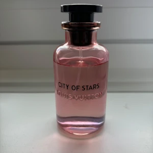 City of Stars parfym från Louis Vuitton - Exklusiv parfymflaska från Louis Vuitton med doften City of Stars. Flaskan är genomskinlig med en rosa ton och har ett svart lock. Elegant och stilren design med märkets logga ingraverad på glaset.