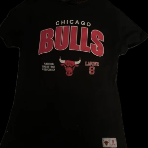 Svart Chicago Bulls t-shirt NBA - Svart t-shirt med stort Chicago Bulls-tryck i rött och vitt framtill. Perfekt för basketfans! Snygg och cool tröja! 