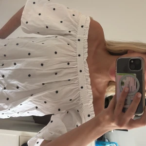 Vit prickig offshoulder topp från H&M - Säljer en  vit offshoulder topp från H&M med svarta prickar och  resår upptill.  Superfin och trendig modell!