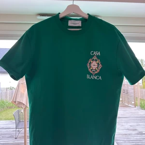 Grön t-shirt från Casablanca med tryck - Snygg grön t-shirt från Casablanca med färgglatt tryck och texten 'Casablanca' både fram och bak. Klassisk passform och rund halsringning. Perfekt för dig som vill sticka ut med en unik design. Storlek M passar S. Skicket är som nytt. 