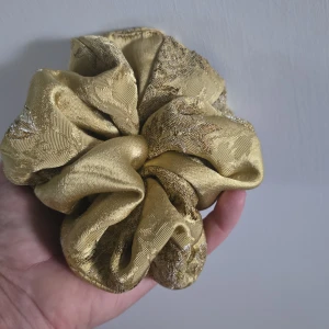 Guldig stor scrunchie/ hårsnodd - Unik snodd då den är egentillverkad/hemsydd. Av ett vackert guldmönstrat tyg som varit en vintageklänning. 