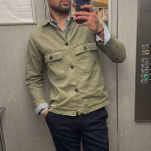 Olivgrön overshirt med fickor - Säljer en stilren olivgrön overshirt med två stora bröstfickor och svarta knappar. NY PRIS 399kr 